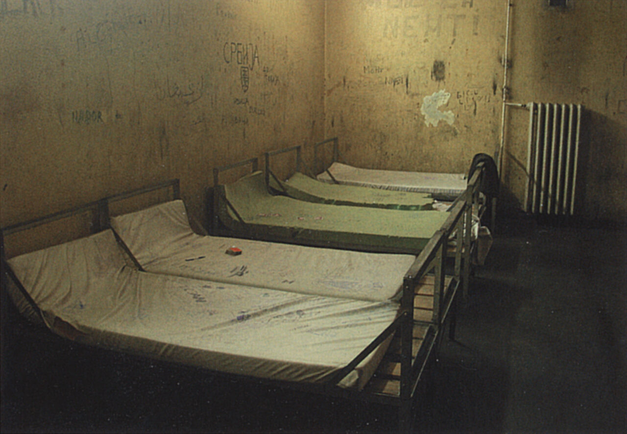 Sammelzelle im 2. Stock des Klapperfelds im Jahr 2001. An der Wand stehen fünf Betten mit verschmutzten Schaumstoffmatratzen.